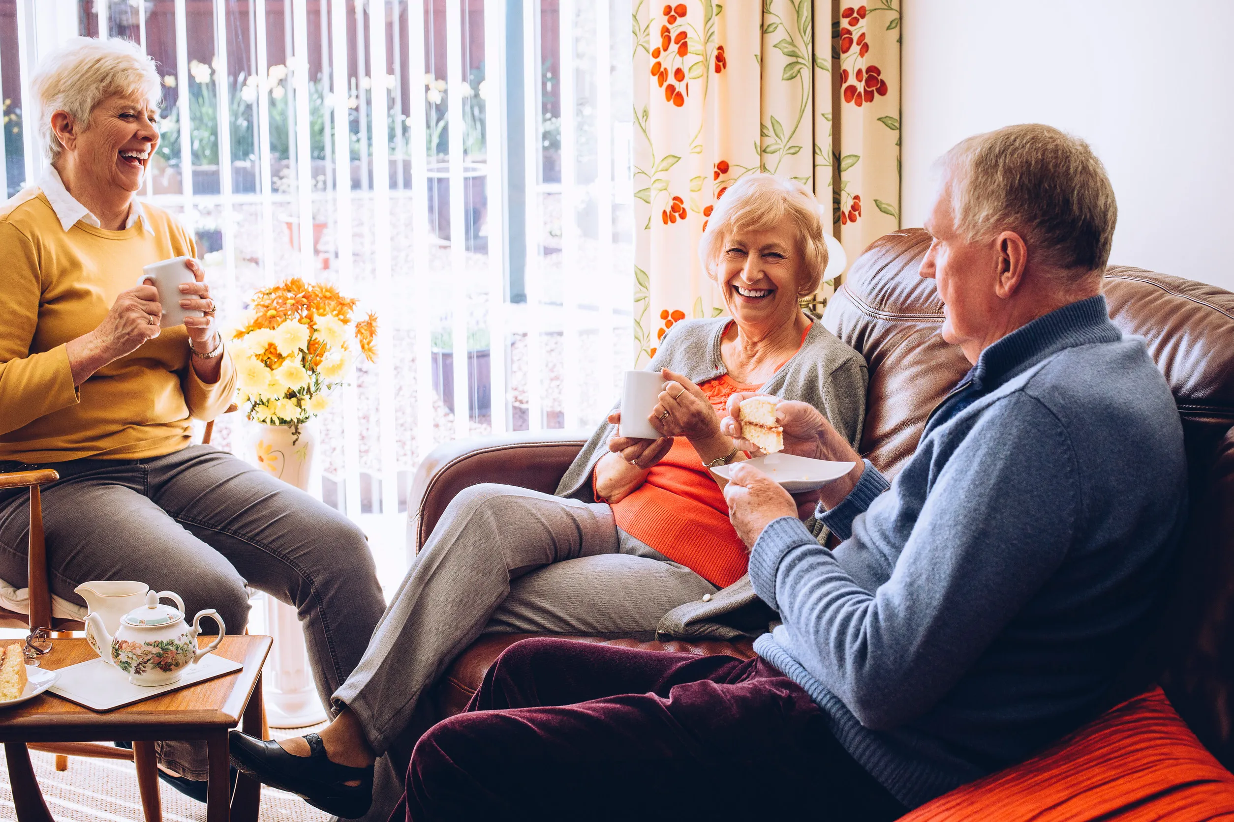 Three seniors enjoying tea and cake in the care home together